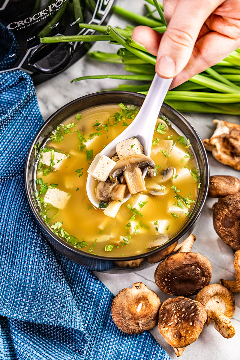 Overhead view of someone holding a spoon filled over a bowl of Chinese hot and sour soup.