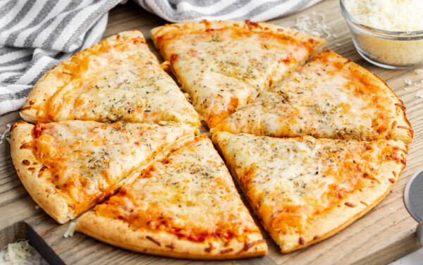 A cheese pizza on a cutting board, cut into 6 pieces.