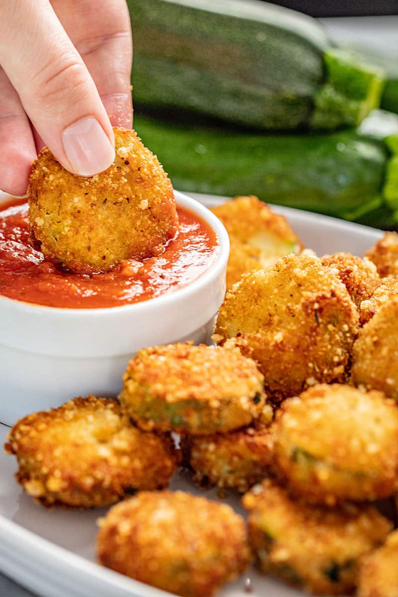 Fried Zucchini being dunked into maranara sauce. 