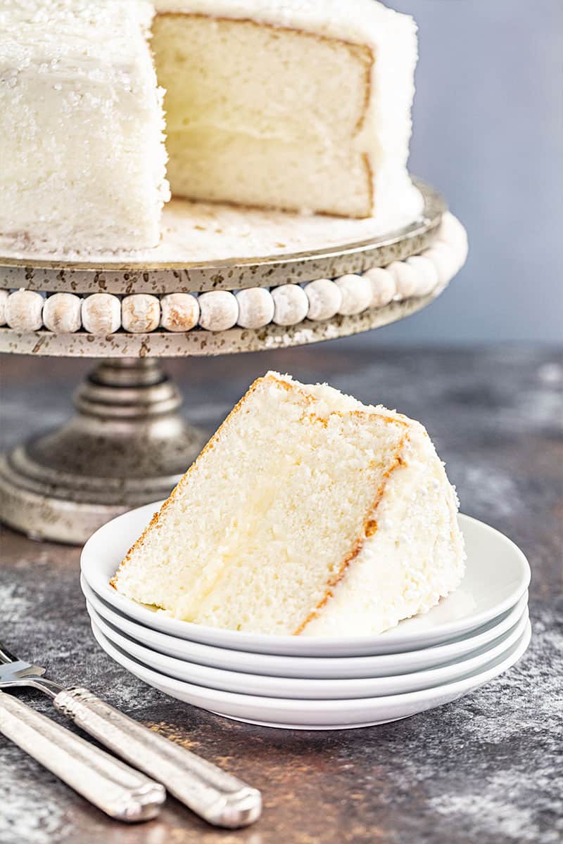 A slice removed from the most amazing white cake on a cake stand.