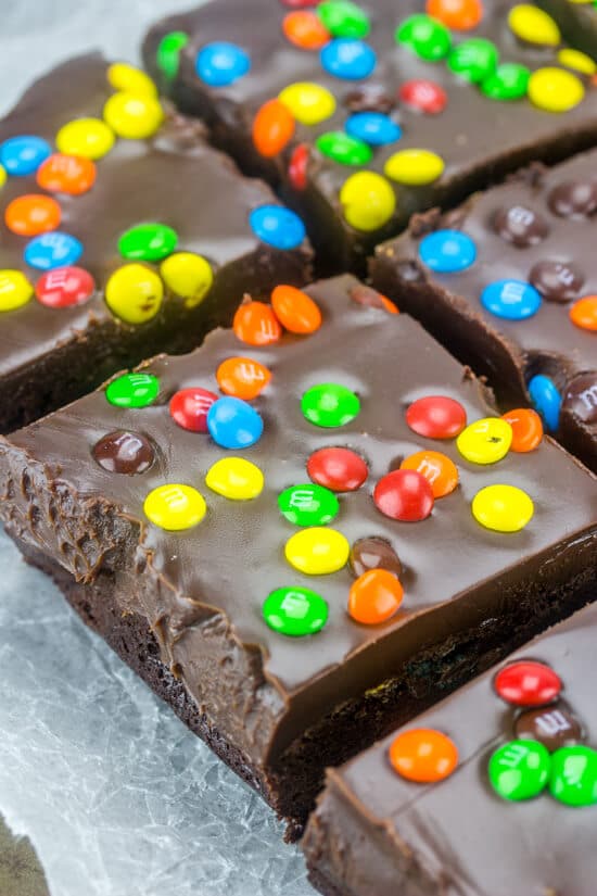 Close up of M&M Fudge Brownies cut into squares on wax paper.