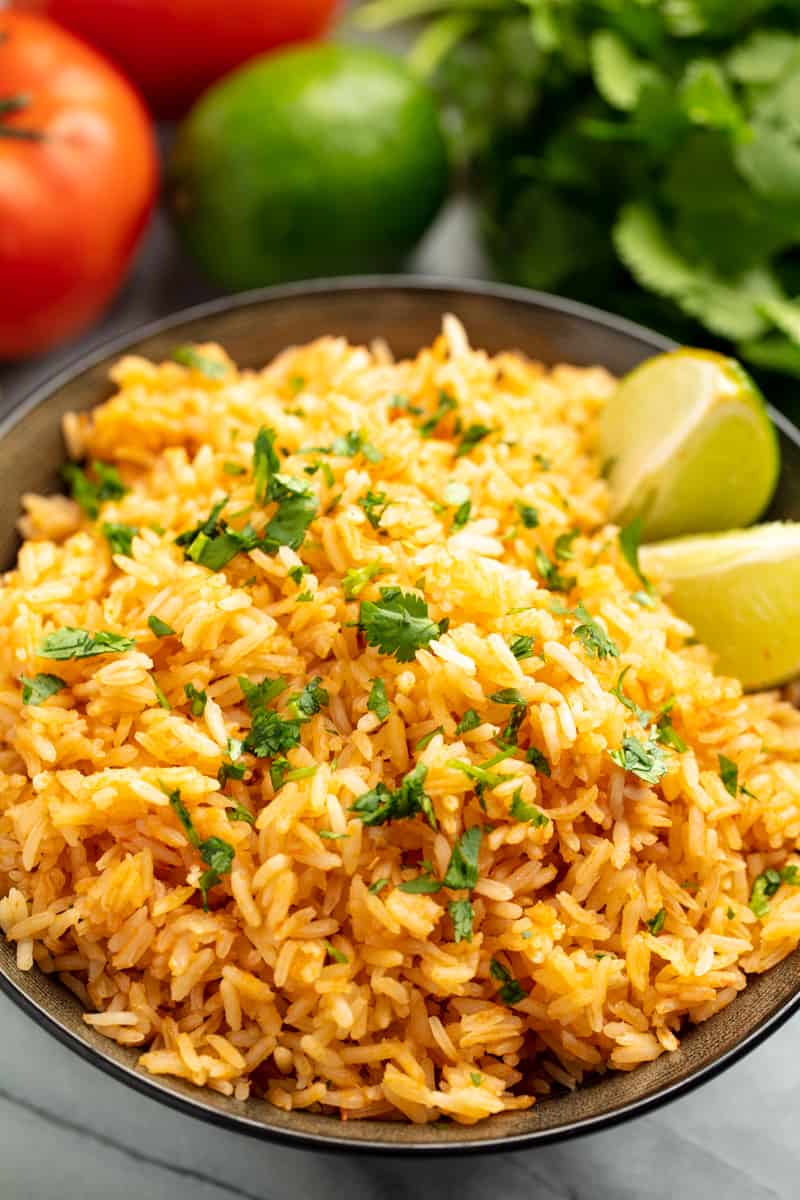 Mexican Rice in a black bowl with two lime wedges.