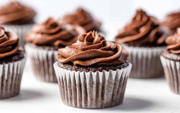 Chocolate cupcakes with chocolate frosting sitting on the counter.