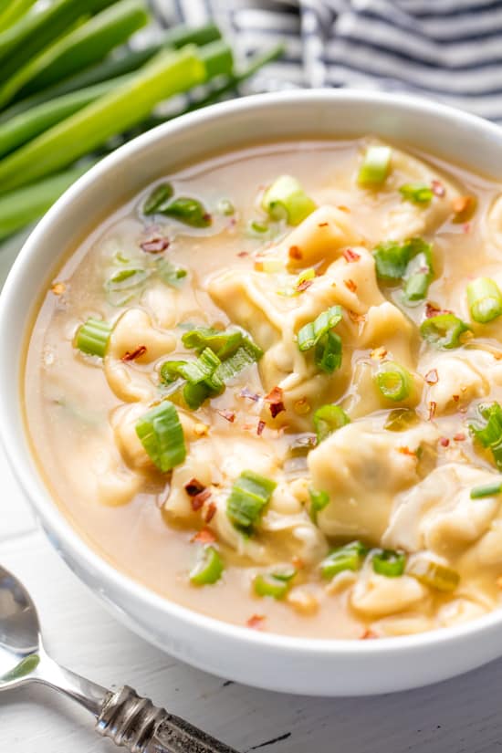 A bowl of Restaurant Style Wonton Soup topped with sliced green onion 