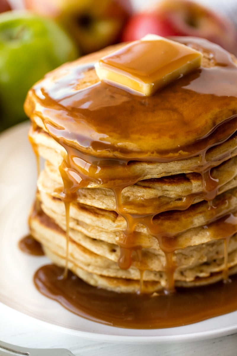 Stack of Apple Pancakes on a white plate topped with a pad of butter and syrup.