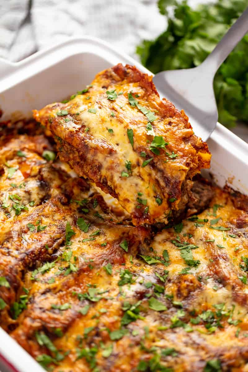 Enchiladas being pulled out of a baking dish with a spatula.