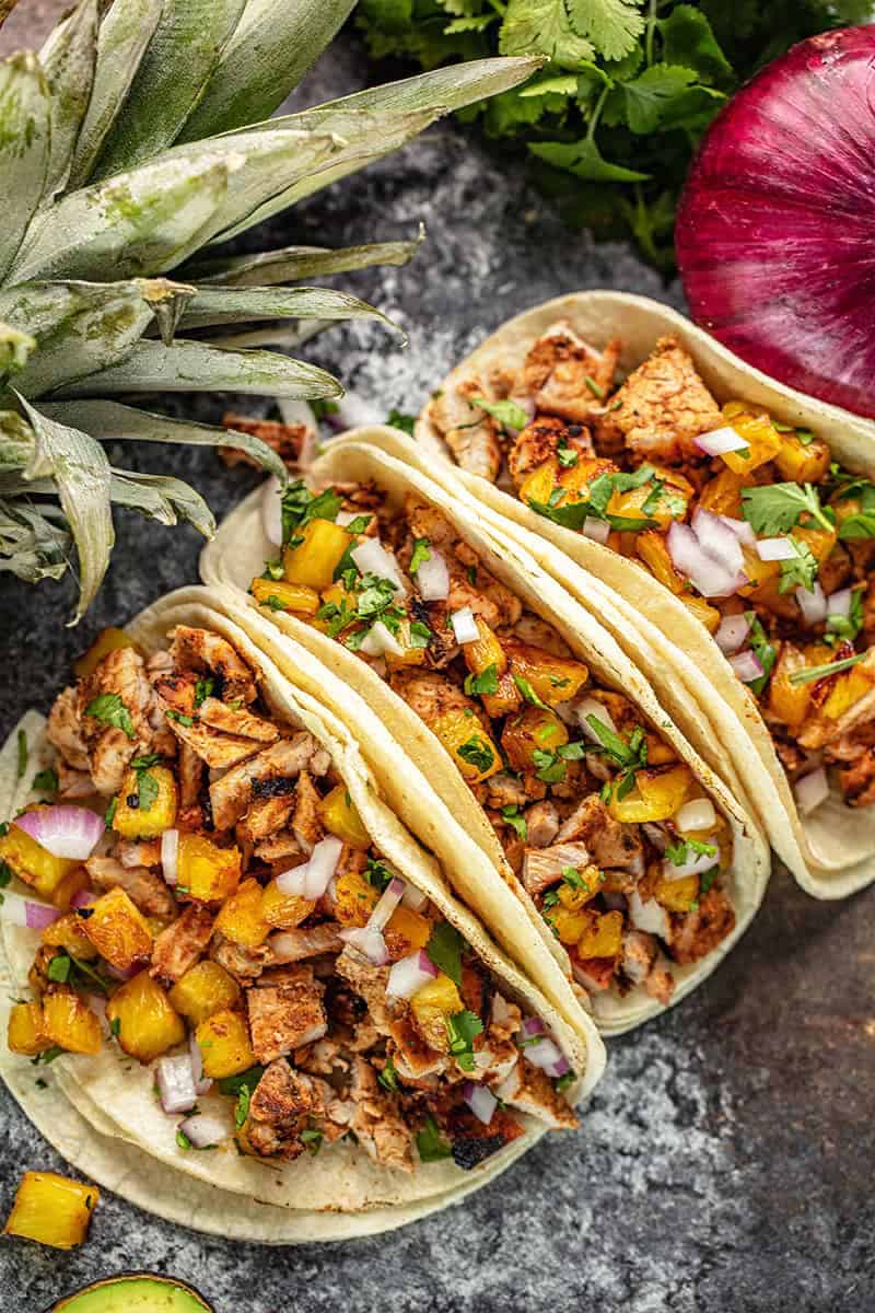 Bird's eye view of Tacos Al Pastor on a black countertop.