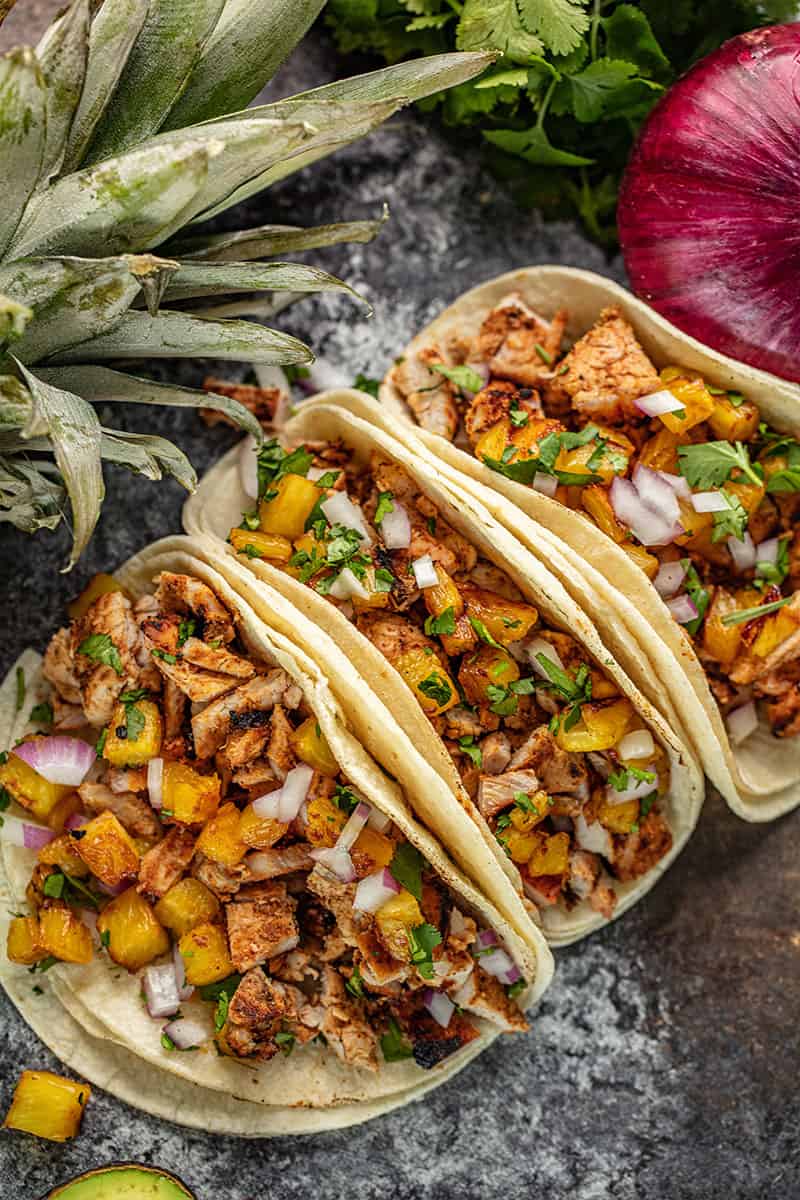 Bird's eye view of Tacos Al Pastor on a black countertop.