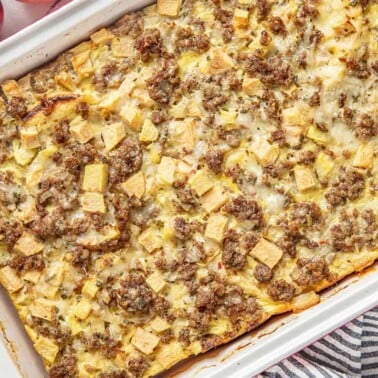 Bird's eye view of Sausage Breakfast Strata garnished with Sage and Apple in a white casserole dish.