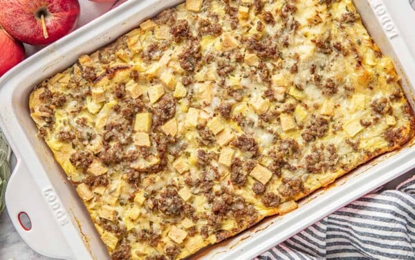 Bird's eye view of Sausage Breakfast Strata garnished with Sage and Apple in a white casserole dish.