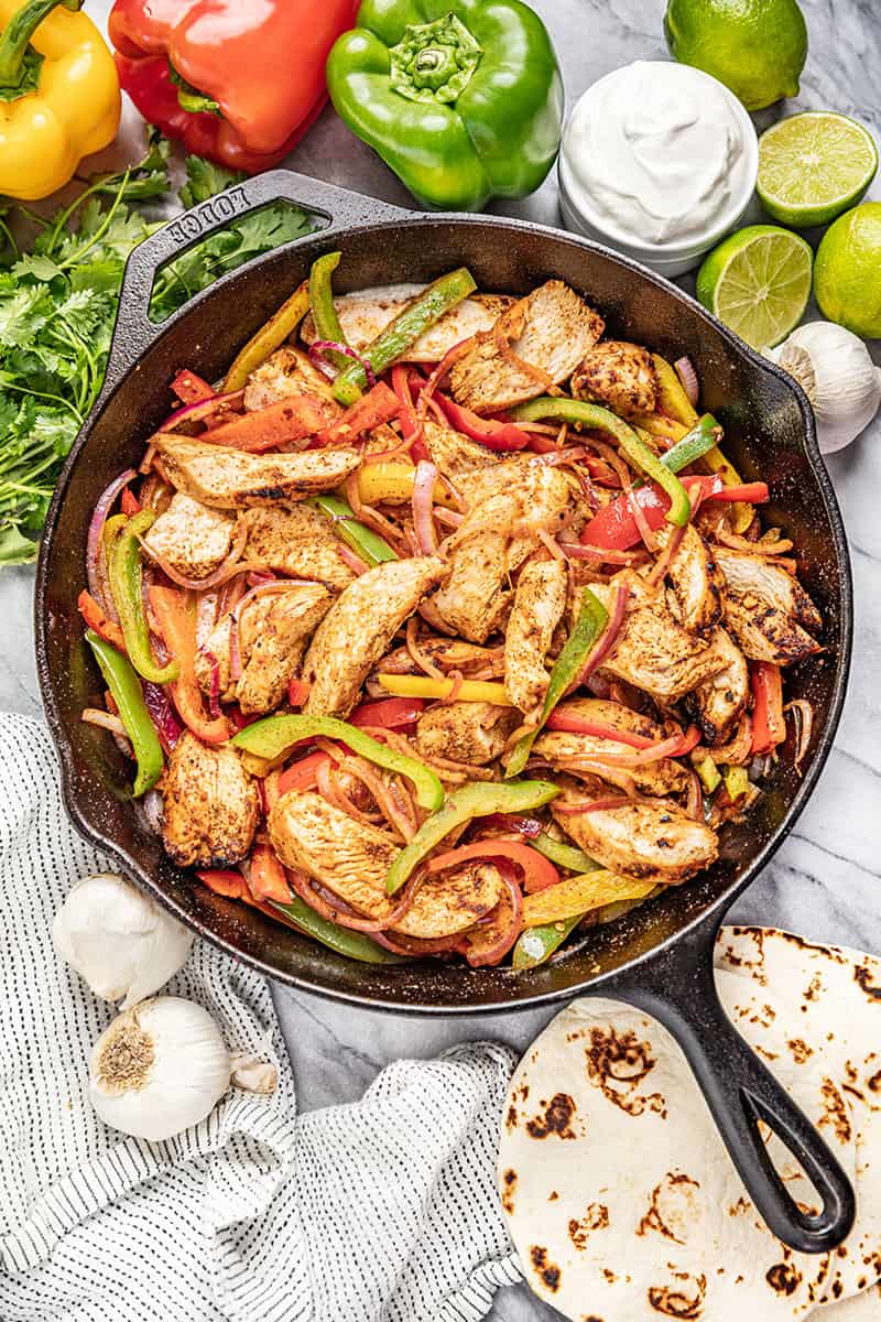 Chicken Fajitas in a cast iron skillet with multi colored bell peppers and onion