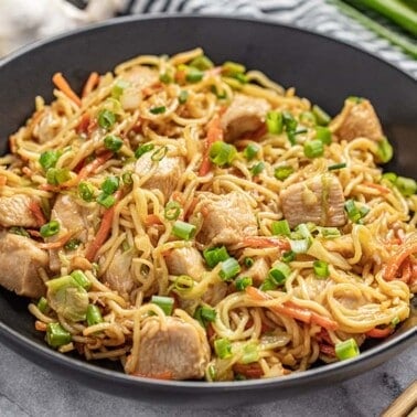 Angled view of Chicken Chow Mein in a black bowl with chopsticks.