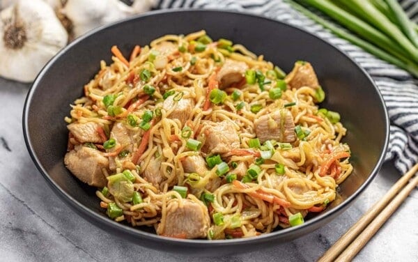 Angled view of Chicken Chow Mein in a black bowl with chopsticks.