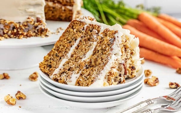 A stack of carrot cake on its side on a stack of white plates