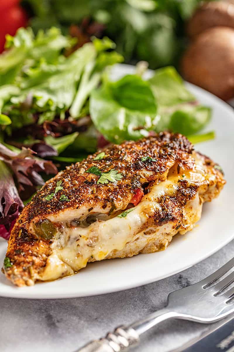 Cajun stuffed chicken breast on a white plate with a side salad