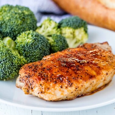 Baked pork chop and broccoli on a white plate.