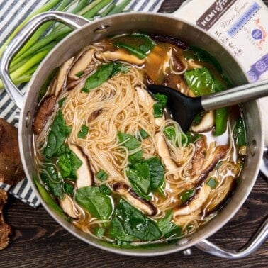 Miso soup in a stainless steel pot with a metal spoon in it.