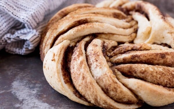 Cinnamon Roll twist bread on a table with a towel by it.