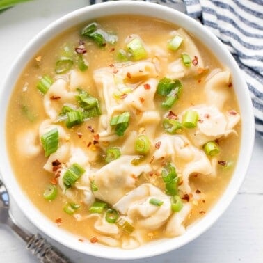 Bird's eye view of wonton soup in a white bowl.