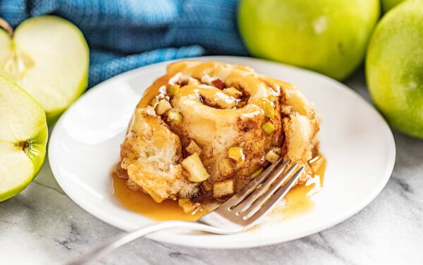 A caramel apple cinnamon roll served on a white plate