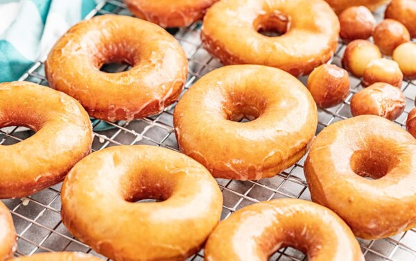 Homemade glazed donuts and donut holes on a cooling rack