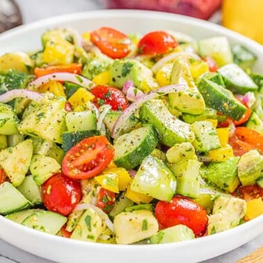 A white serving bowl filled with tomato and avocado salad.