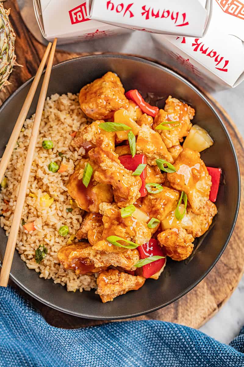 Sweet and sour chicken and rice in a black bowl.