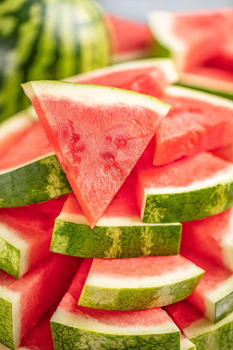 Large stack of watermelon cut into triangles.