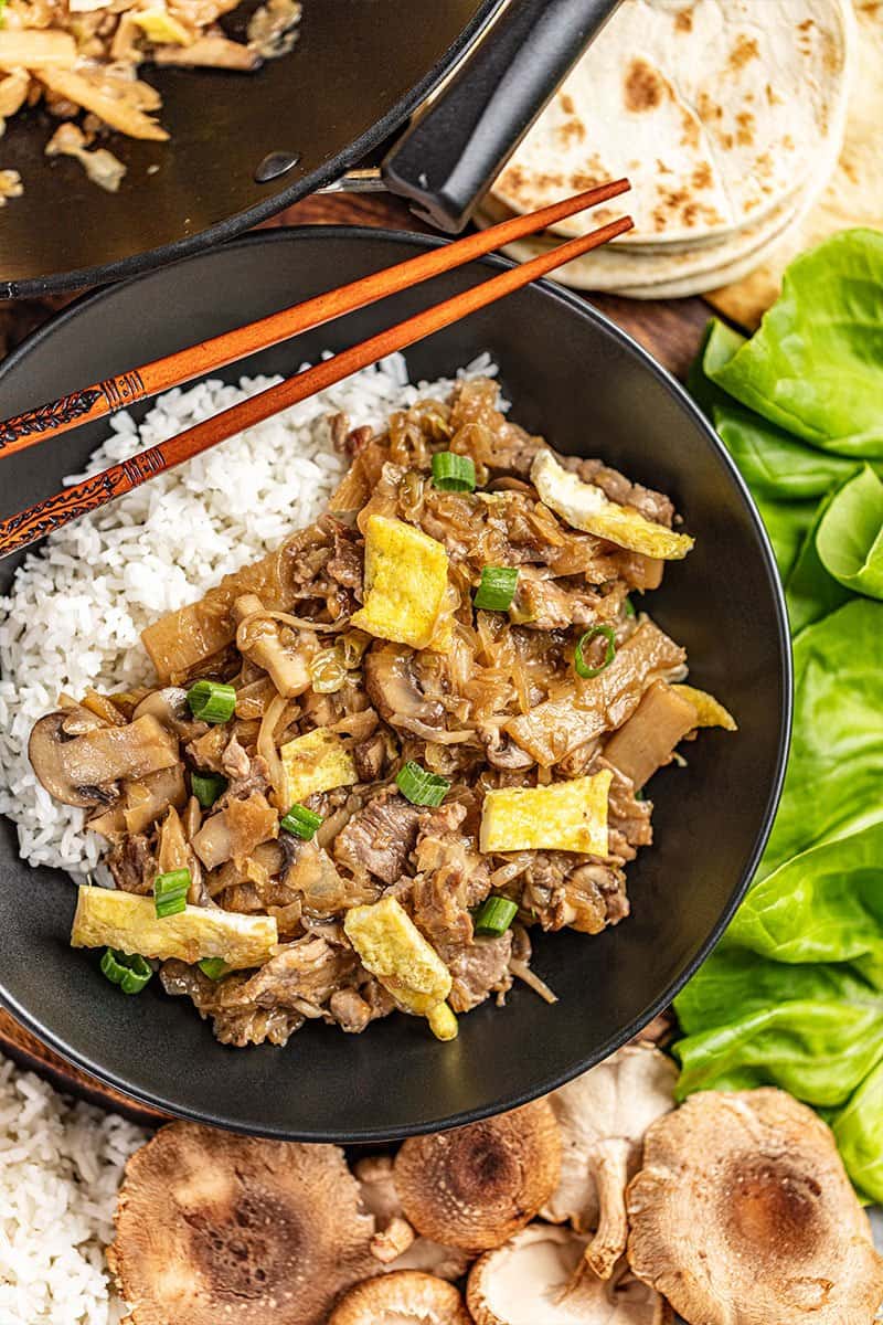 Overhead view of moo shu pork and white rice in a bowl.