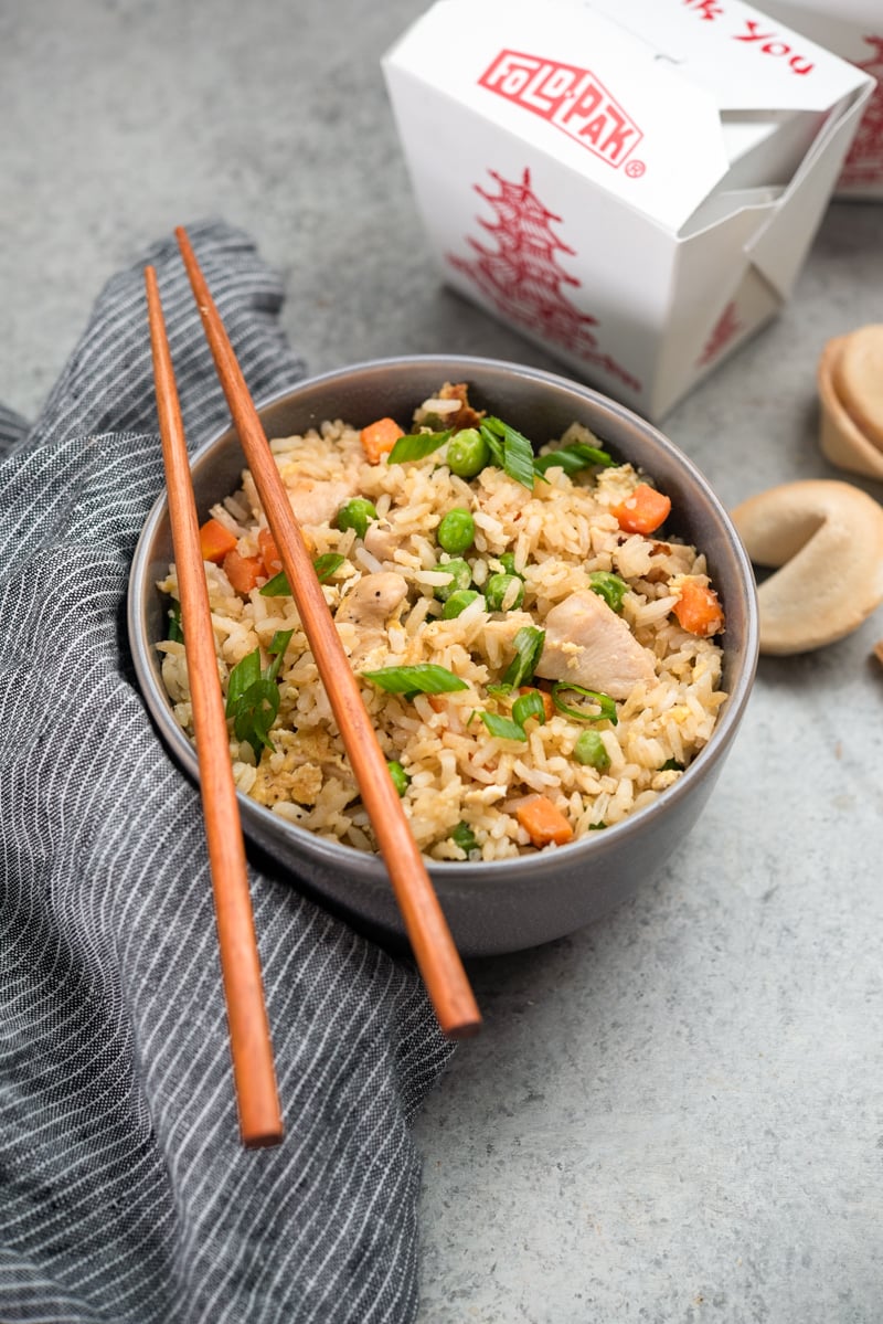 Bowl of chicken fried rice with chopsticks resting on top.