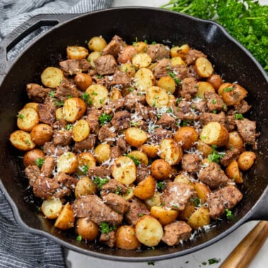 Looking into a cast iron pan with steak bites and potatoes.