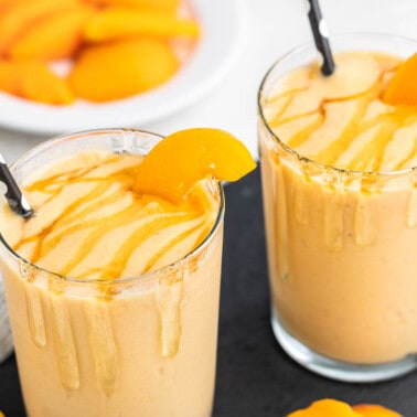 Close up view of two glasses filled with peach smoothies.